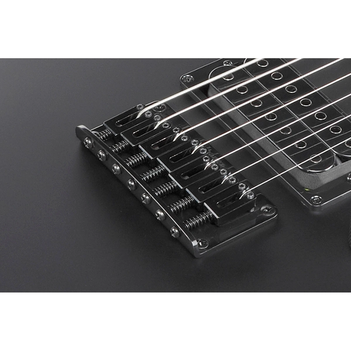 Primer plano de la tapa arqueada de arce flameado y el puente fijo F107 de la guitarra de 7 cuerdas Ibanez RGA742FM-TGF.